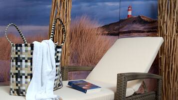 Relax in a cozy space with a wicker lounge chair, a book, and a beautiful lighthouse photograph.