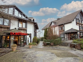 Ein Hotel namens „DORNERHO“ mit überdachter Außenbestuhlung und Blumentöpfen.