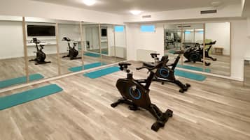 A gym with stationary bikes, mirrors, and exercise mats.