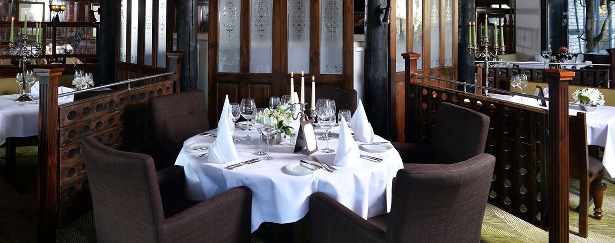 Ein Restaurant mit runden Tischen, gedeckt für ein Essen, mit weißen Tischdecken und Besteck.