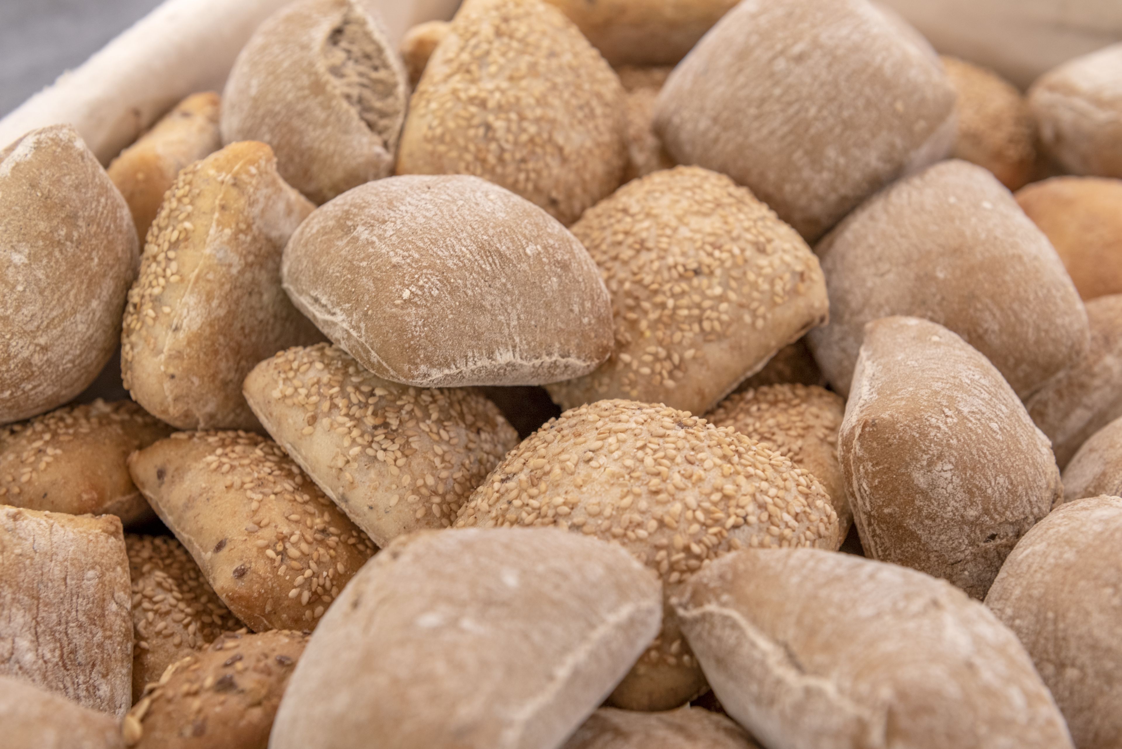 A close-up of various types of bread, including some with sesame seeds.