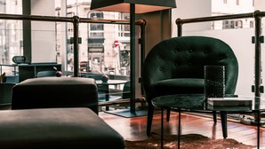 Een moderne woonkamer met een groene fauteuil, een glazen salontafel en een zwarte vloerlamp.