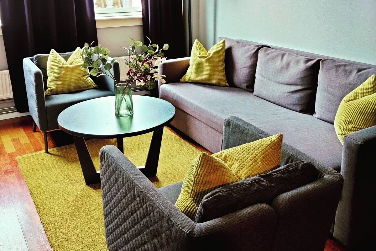 A modern living room with a grey sofa, two armchairs, a round coffee table, and a floor lamp.