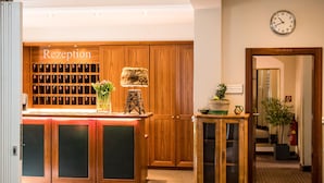 Un área de recepción con armarios de madera, un mostrador, un reloj y un espejo.