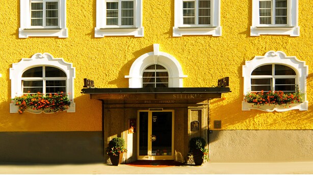 Un edificio amarillo con varias ventanas y una entrada principal.