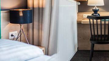 A hotel room with a bed, a desk, a chair, and a lamp.