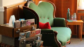 Ein grüner Sessel mit einem roten Kissen, ein Stapel Koffer und eine Bücherwand voller Bücher.