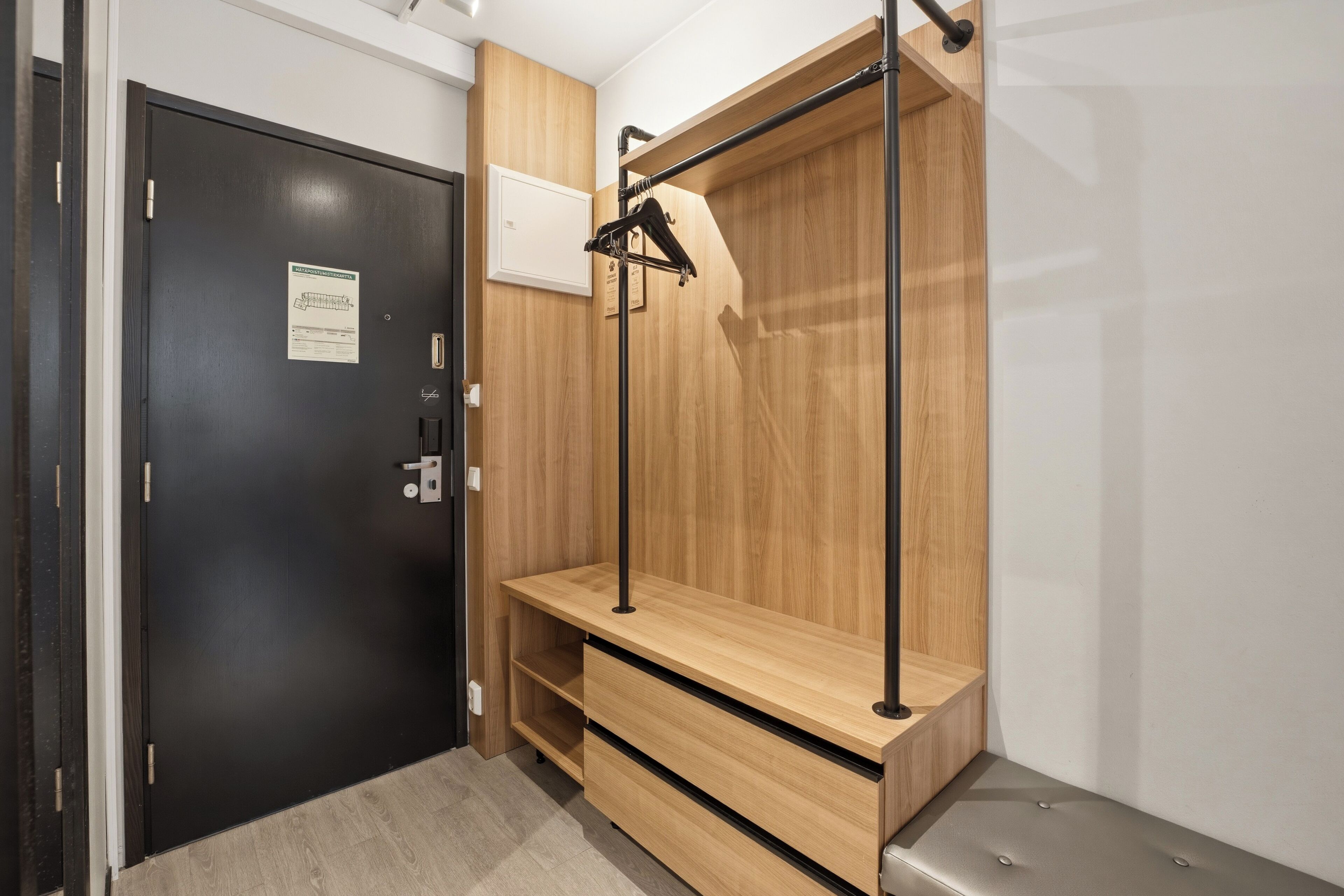 A room with a wooden wardrobe, a bench, and a door with a sign.