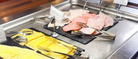 A buffet with various cheeses, meats, and sliced cucumbers.