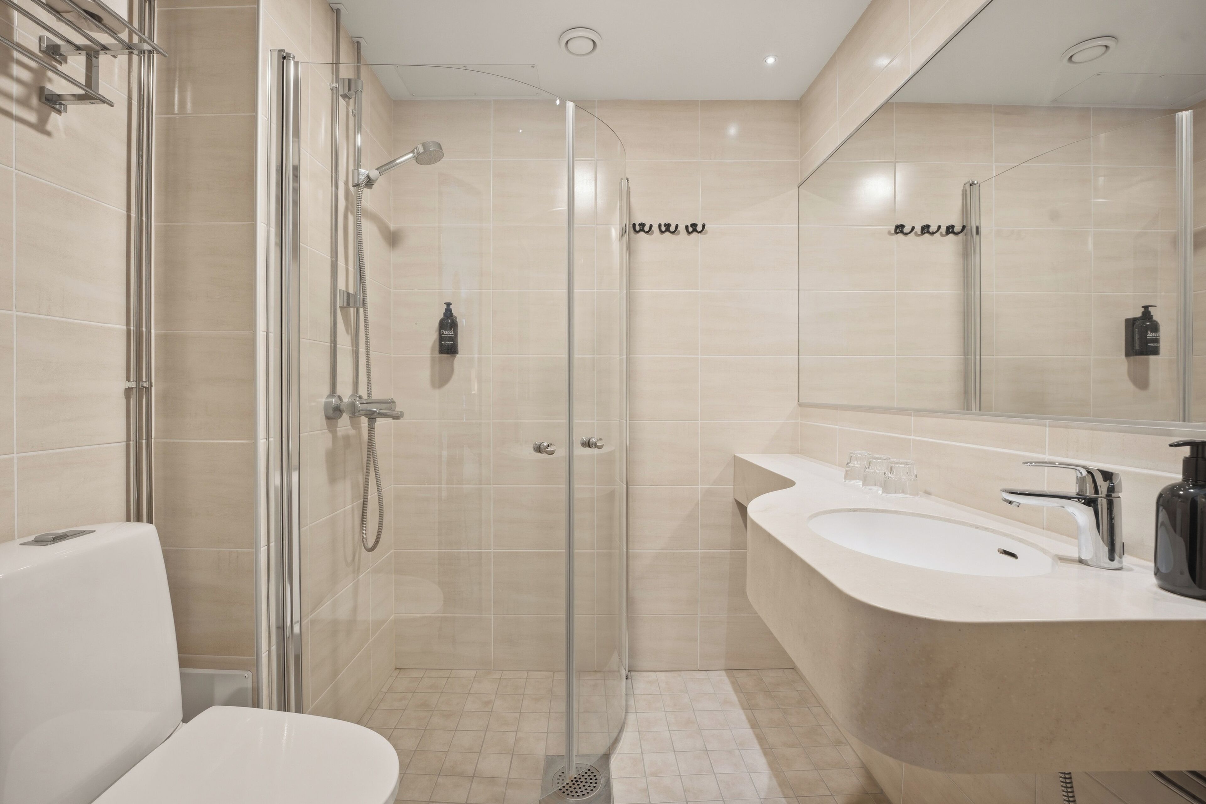 Une salle de bain moderne avec une douche à parois de verre, un lavabo blanc et un grand miroir.