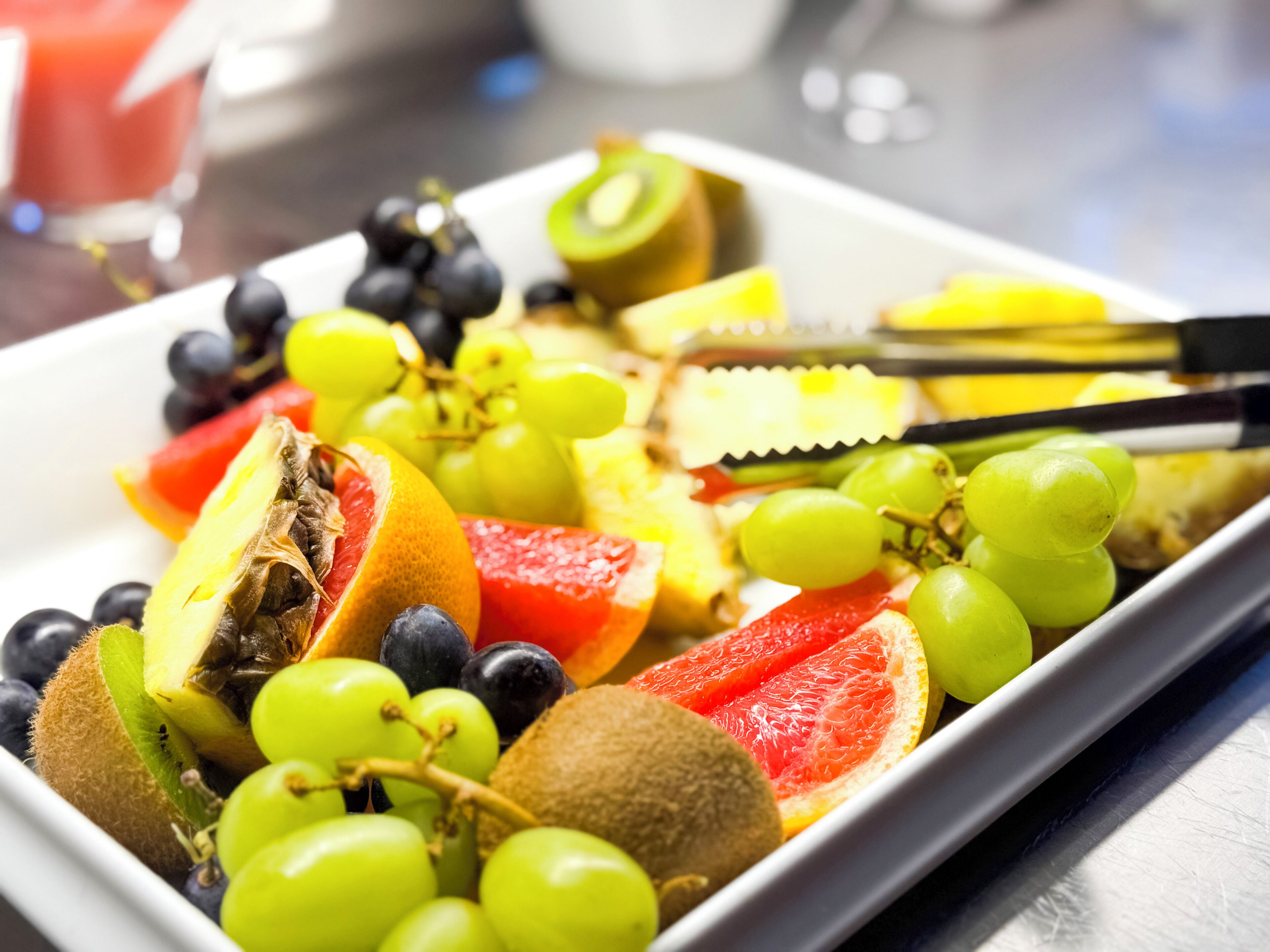 A fruit platter with various fruits and a knife.