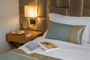 A hotel room with a bed, a bedside table with a lamp, a plate of fruit, and a book.