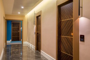 A hallway with a marble floor, wooden doors, and a blue accent wall.