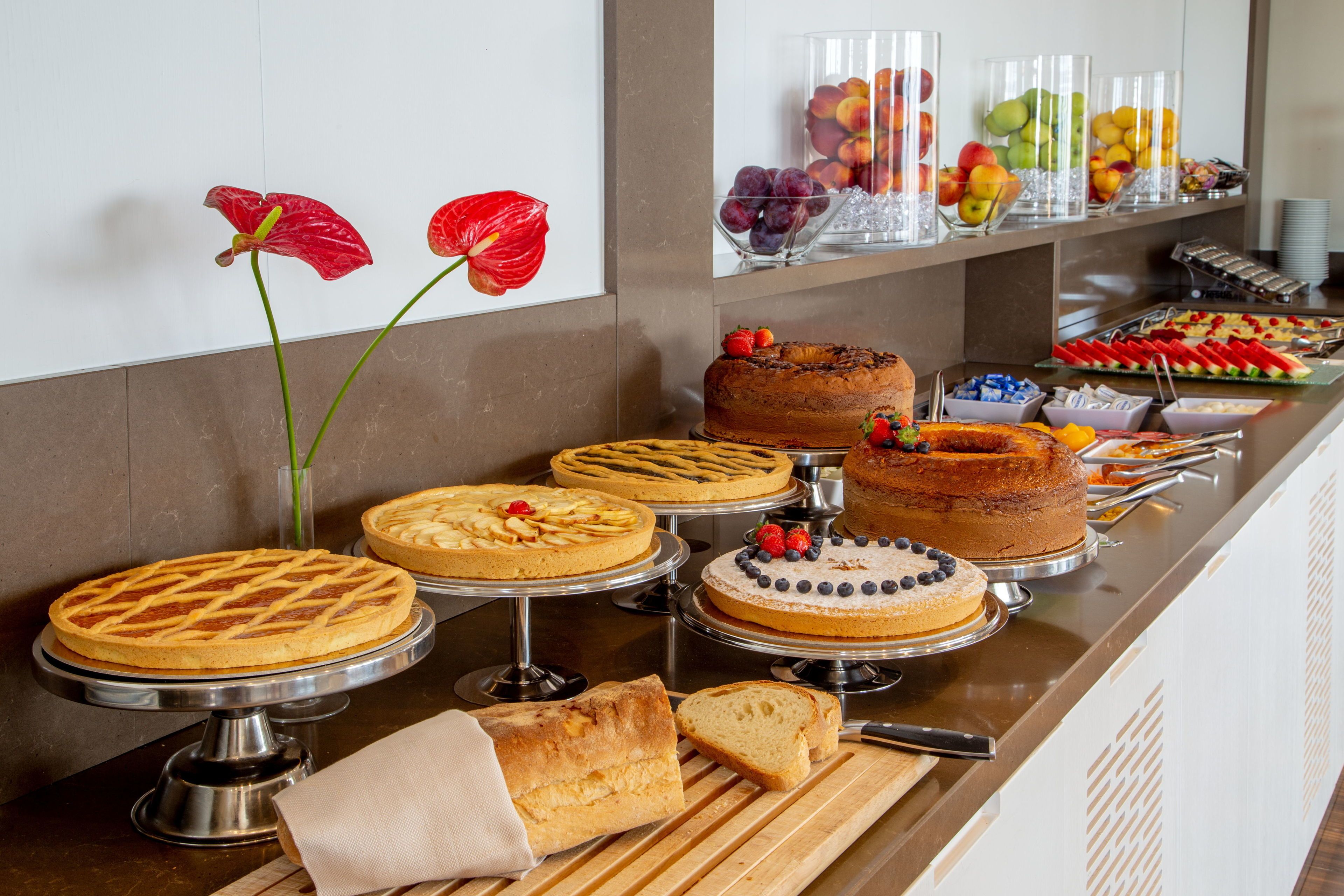 A buffet with various cakes, pastries, and fruits.