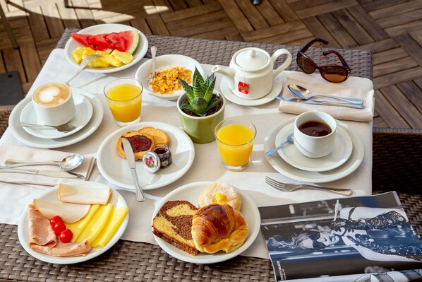 A breakfast table with plates of food, a teapot, cups, and a magazine.
