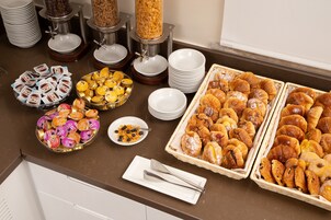 A buffet with various food items including pastries, fruits, and condiments.