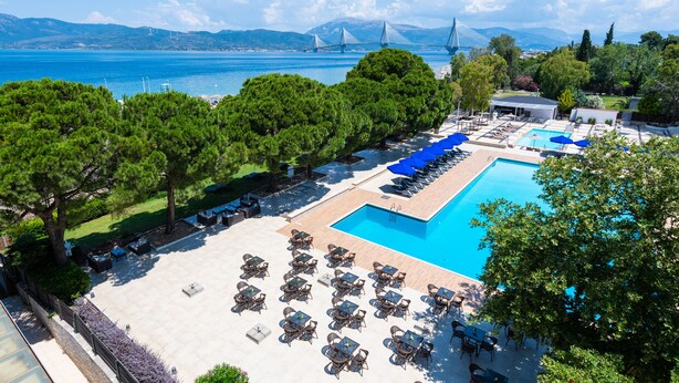 Ein Resort mit großem Pool, Sitzgelegenheiten im Freien und Blick auf eine Brücke und Berge.