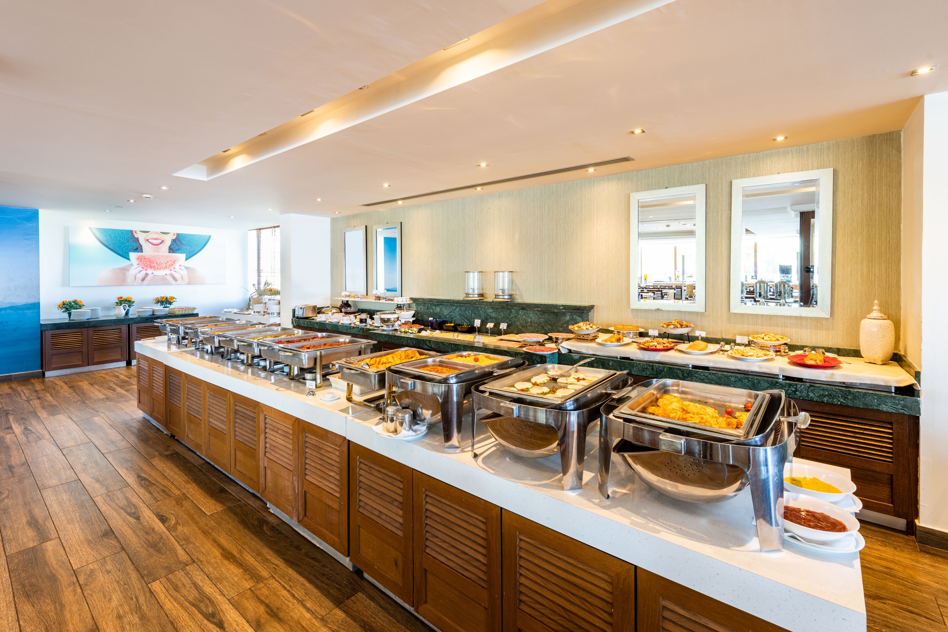 Monipuolinen buffetpöytä, jossa on useita ruokapisteitä ja pitkä tarjoilutaso.