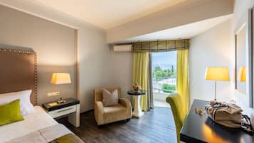A hotel room with a bed, a chair, a desk, and a view of a cityscape.