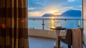 Ein Balkon mit Blick auf das Meer und die Berge im Sonnenuntergang.