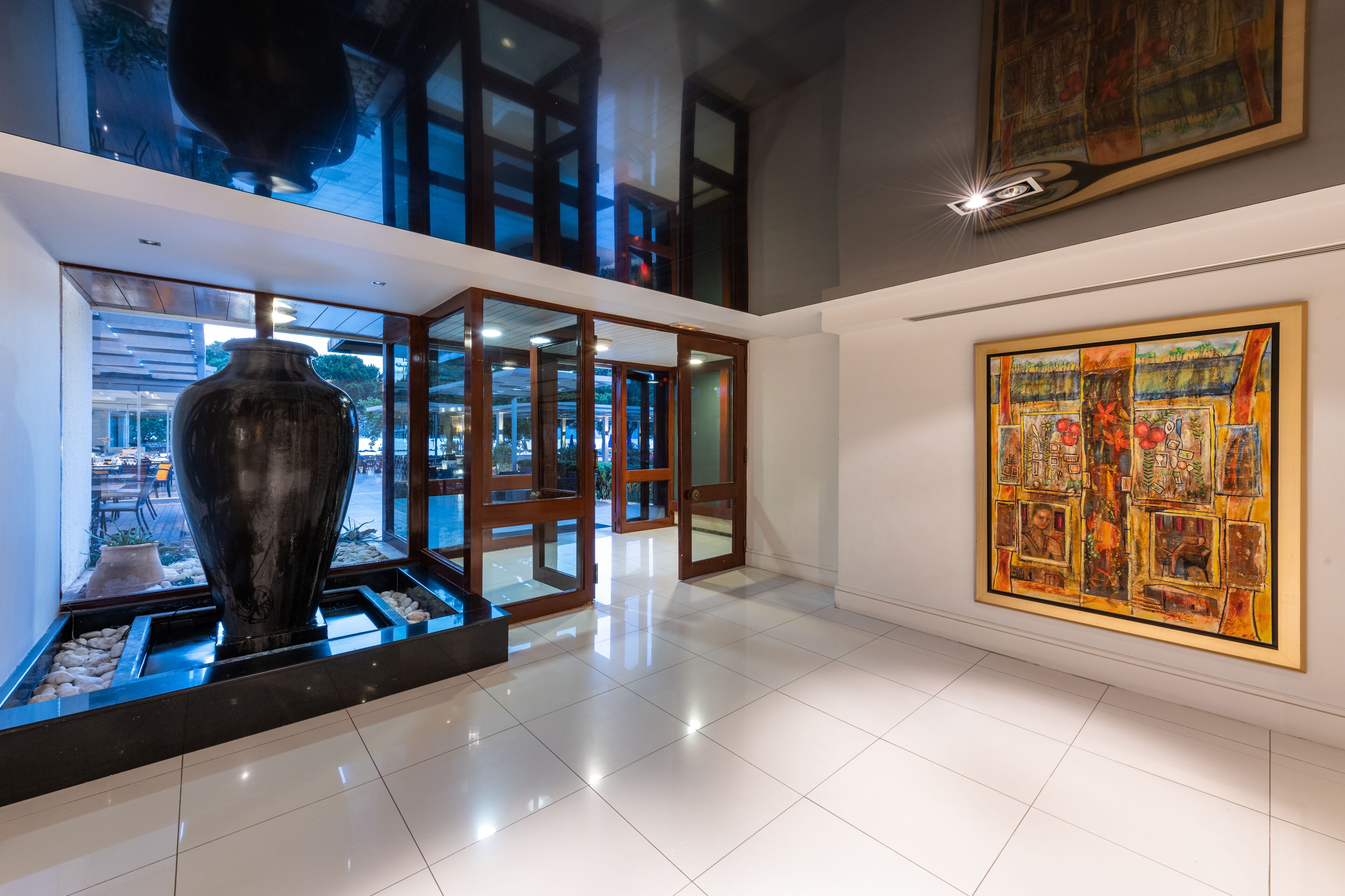 Ein modernes Interieur mit einer großen Vase, Glaswänden und einem farbenfrohen Gemälde.