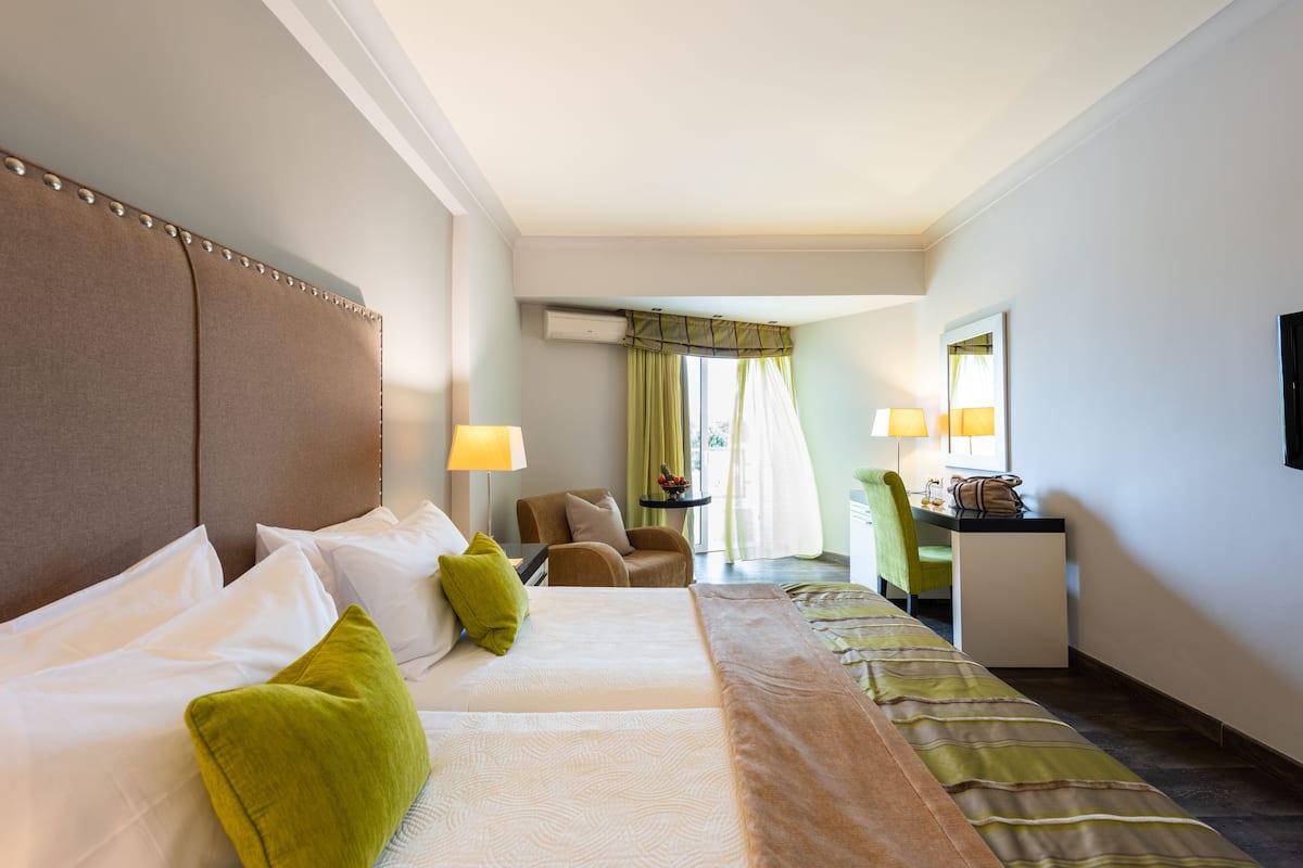 A hotel room with a large bed, a desk, and a chair.
