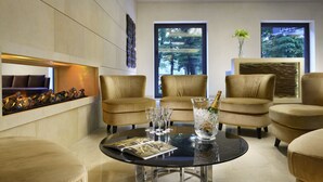 A modern lounge area with a glass coffee table, leather armchairs, and a fireplace with a stone accent wall.