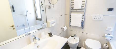 A modern bathroom with a large white sink, a bidet, and a toilet.