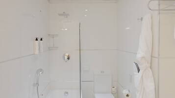 A modern bathroom with a bathtub, toilet, and glass shower enclosure.