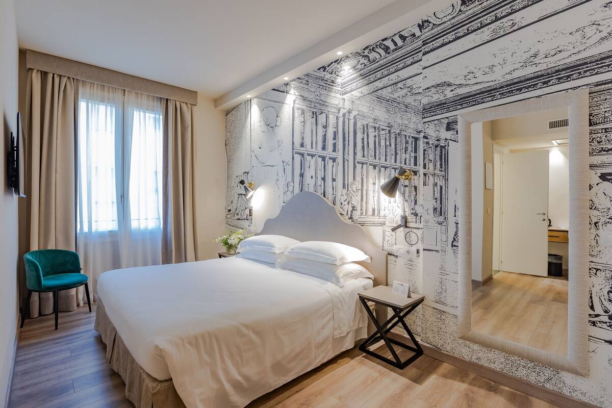 Une chambre d’hôtel avec un grand lit, un bureau, une chaise et un miroir.