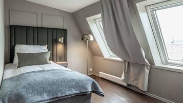 A modern bedroom with a bed, a nightstand, a lamp, and a window with curtains.
