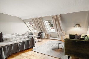 Un dormitorio tipo loft moderno con una cama, un sillón verde, una mesita y una lámpara.