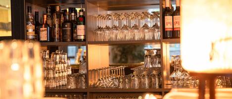 A bar area with shelves of liquor bottles and a collection of wine glasses.