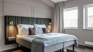 Un dormitorio moderno con una cama grande, mesitas de noche y vistas al exterior a través de una ventana.