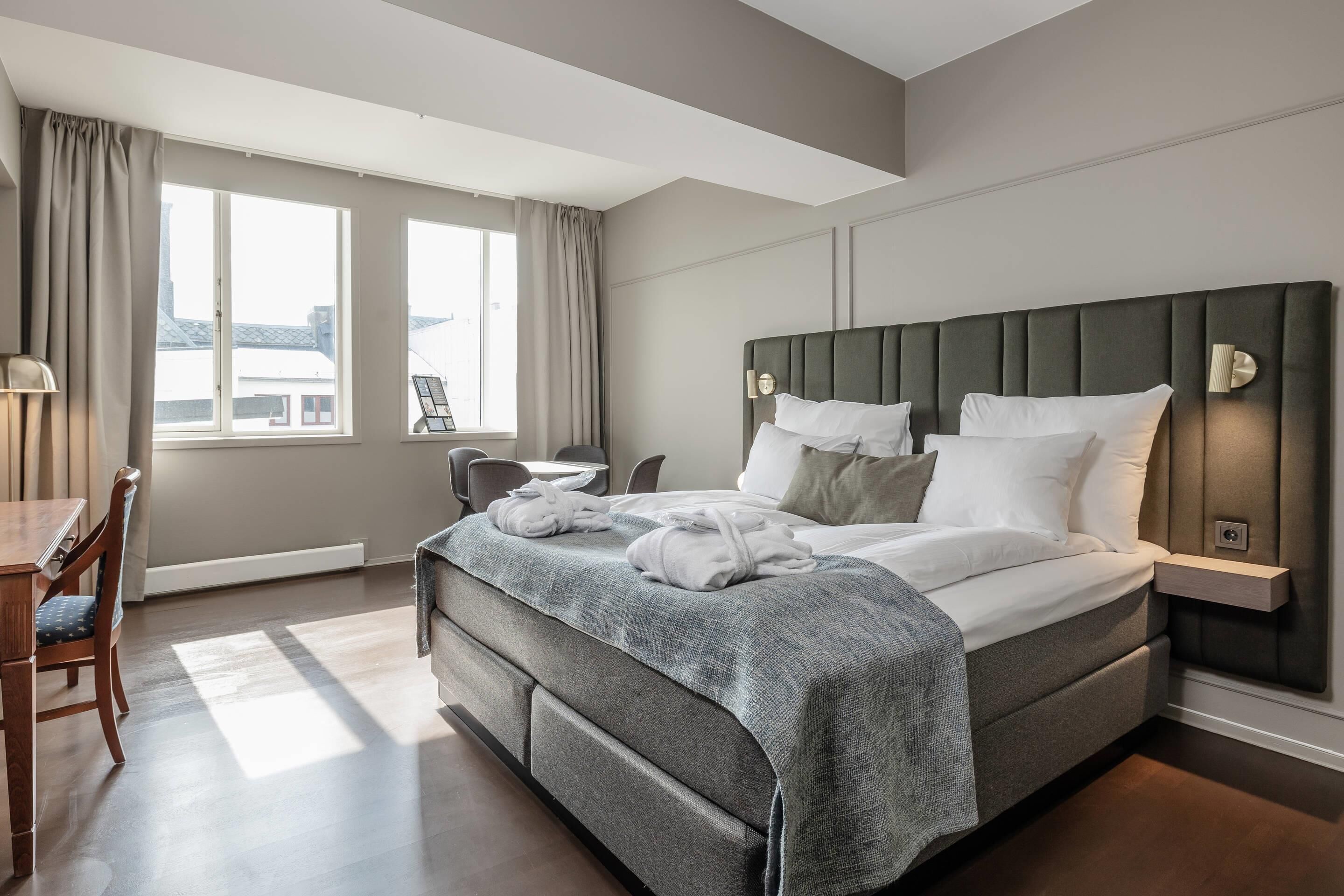 Una habitación de hotel moderna con una cama grande, un escritorio y una silla.