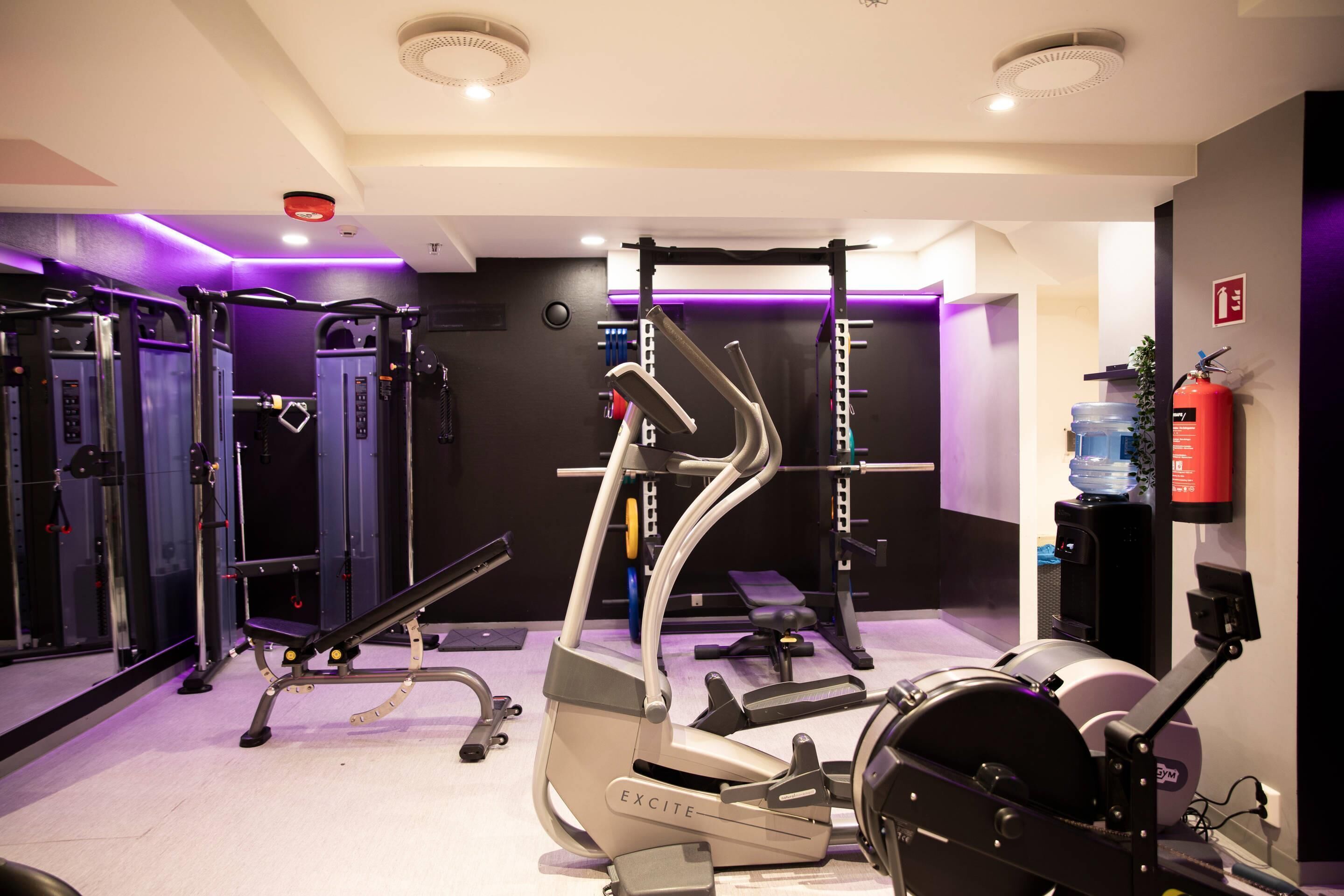 A gym with various exercise equipment, including a treadmill, weight machines, and a pull-up bar.