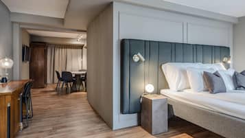 A modern hotel room with a large bed, a small desk, and a dining area.
