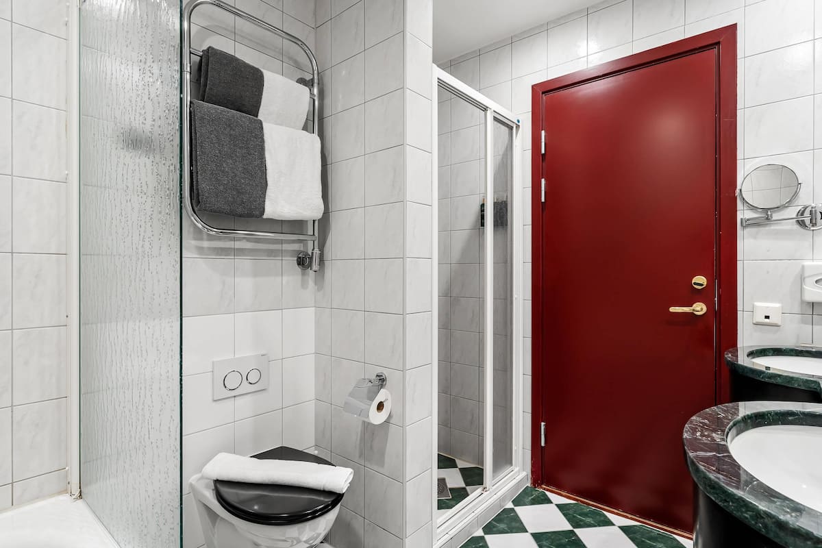 Ein Badezimmer mit Dusche, Toilette und zwei Waschbecken.