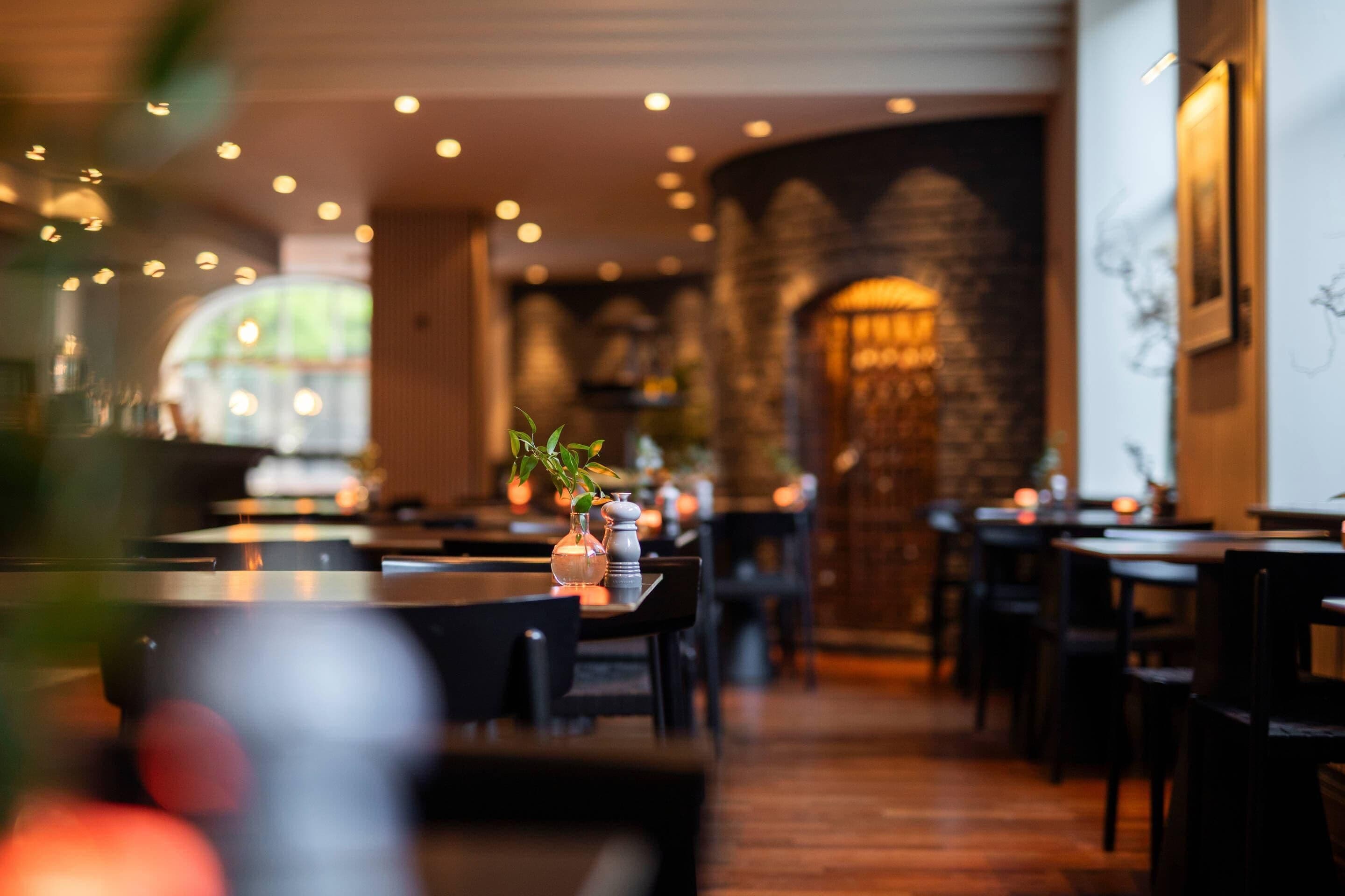A restaurant interior with tables, chairs, and a brick wall.