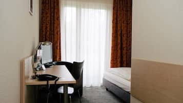 Una camera d'albergo con una scrivania, una sedia e un letto.