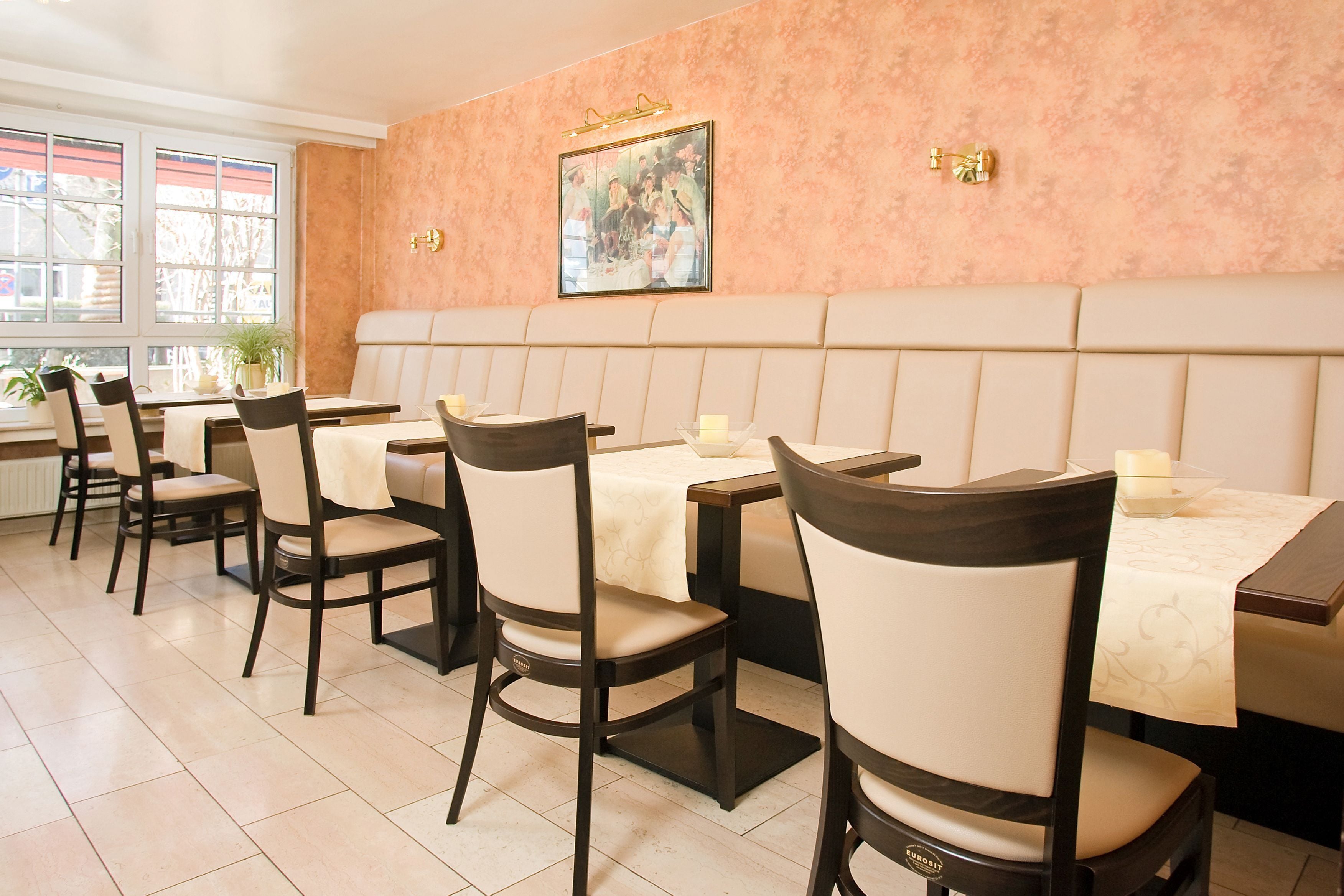 Un restaurant avec un long comptoir, des chaises rembourrées et un tableau accroché au mur.
