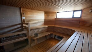 A sauna with wooden benches and a tiled floor, a window for natural light, and a metal bucket on one bench. - Scandic Patria (Lappeenranta)