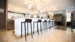 A modern bar area with a long counter and multiple stools. - Scandic Patria (Lappeenranta)