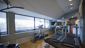A gym with various exercise equipment, large windows, and a wooden floor. - Scandic Patria (Lappeenranta)