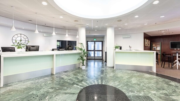 A modern reception area with a marble floor, white reception desks, and pendant lighting. - Scandic Patria (Lappeenranta)