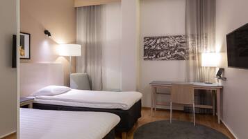 A hotel room with two beds, a desk, a chair, a TV, and a large window with curtains.