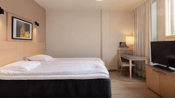 A hotel room with a bed, a desk, a TV, and a picture on the wall.