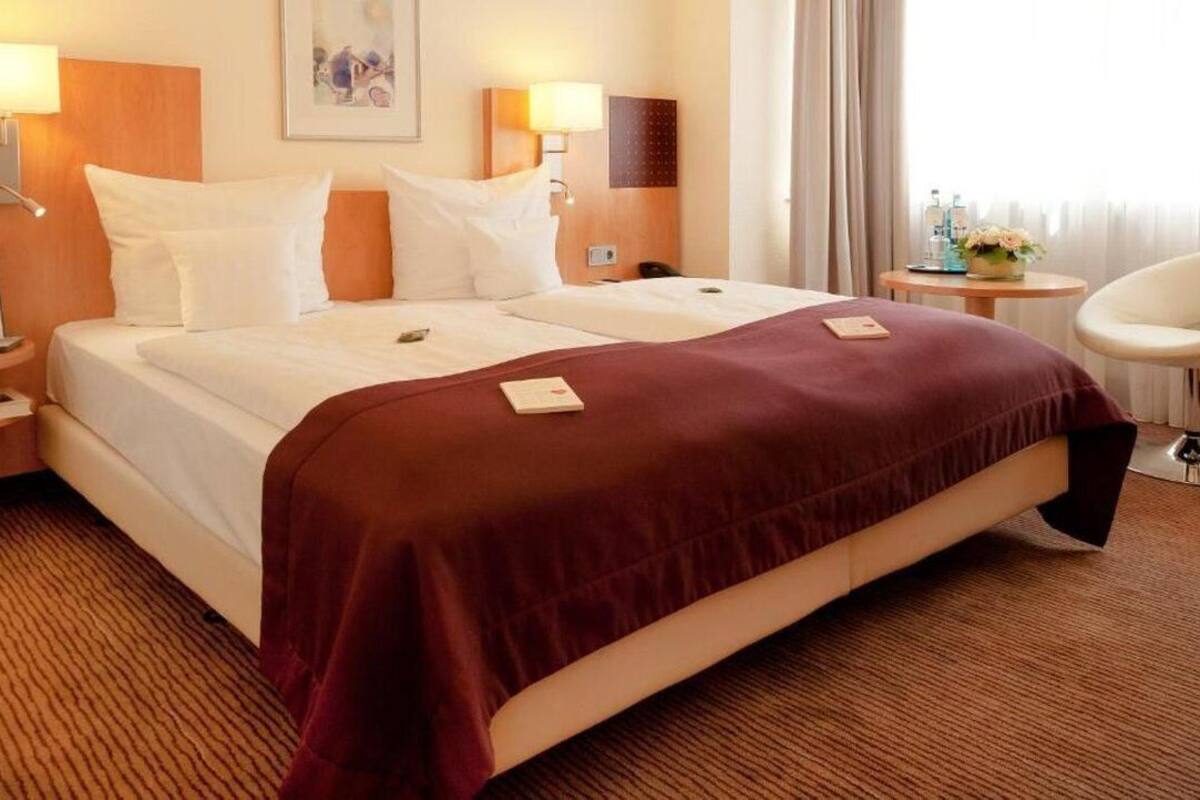 A hotel room with a large bed, two bedside tables, a chair, and a small table with a vase of flowers.