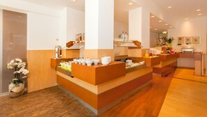 A modern hotel lobby with a reception desk, seating area, and a large mirror.