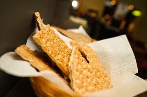 Una cesta de barras de pan cortadas con semillas de sésamo sobre una mesa.